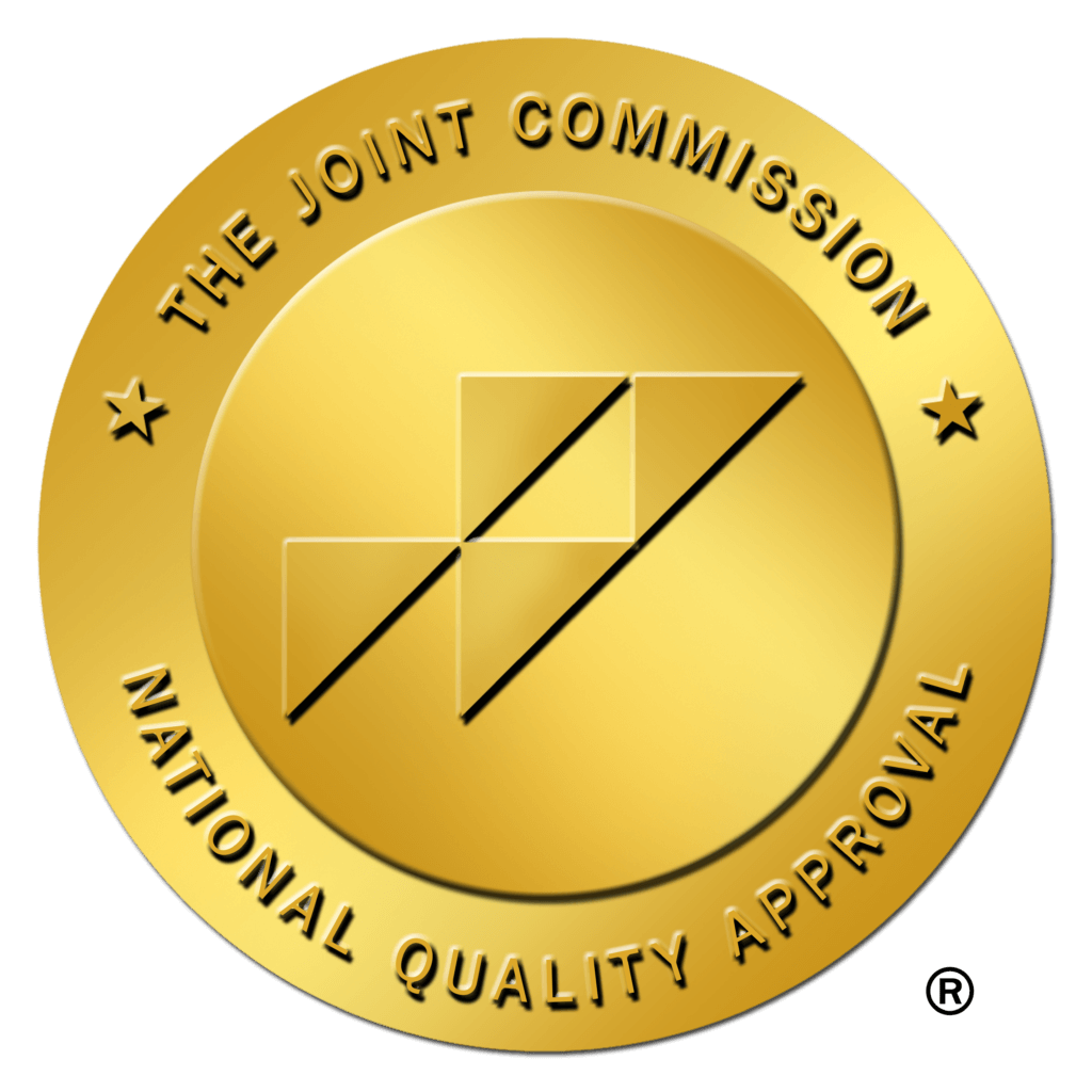 Gold medal badge inscribed with The Joint Commission National Quality Approval around the edge, featuring a geometric central emblem.